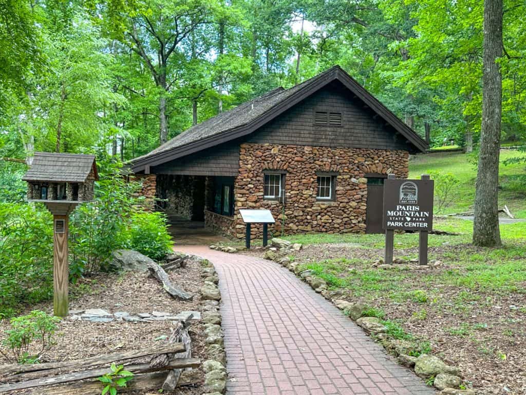 A quaint stone building labeled as Paris Mountain State Park Center, nestled in a serene wooded area.