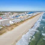 A sweeping aerial view of Carolina Beach, with the beach on one side and the town on the other, highlighting the density of buildings and the long, narrow strip of the beach.