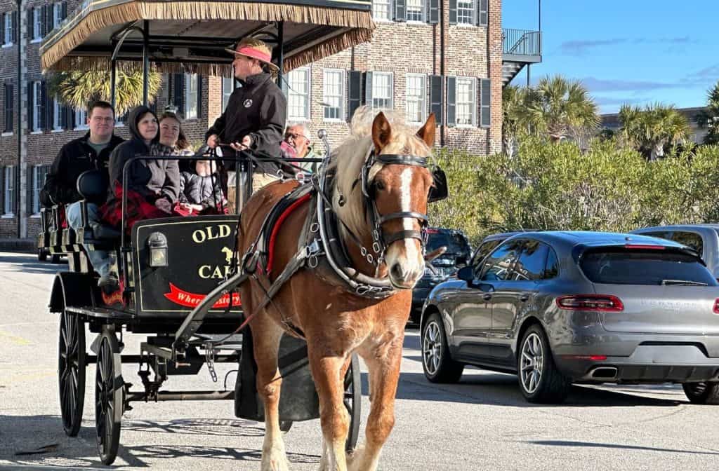 Horse Carriage ride coming down the street with people on the cart.
