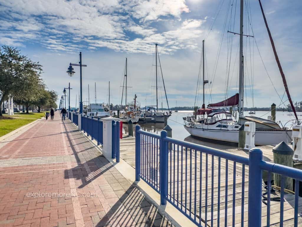 Riverfront walk with boats in the background