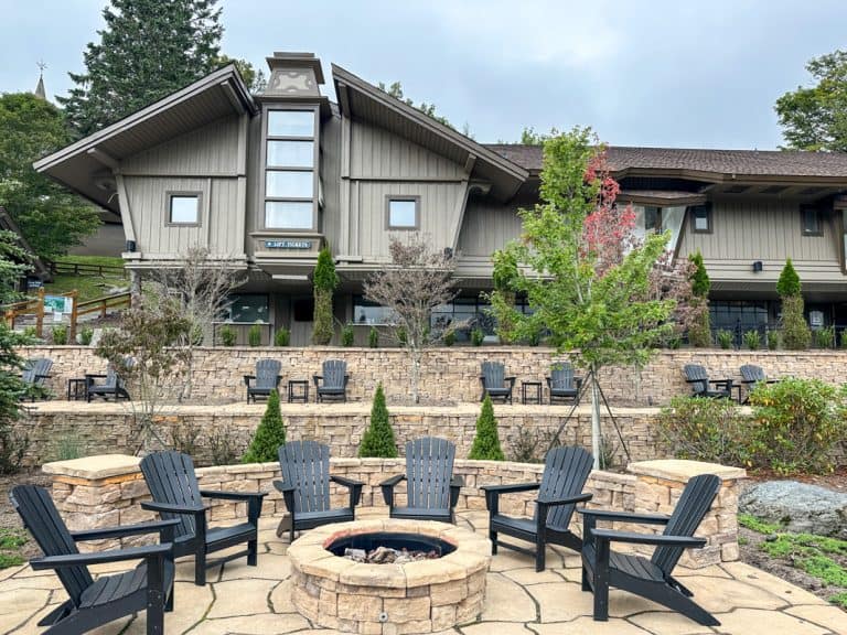 Outdoor seating area at Beech Mountain Resort Village with Adirondack chairs and a fire pit surrounded by landscaped terraces.