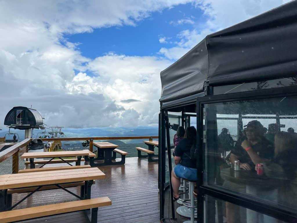 Outdoor deck at Beech Mountain Skybar with picnic tables, mountain views, and a covered seating area under cloudy skies.