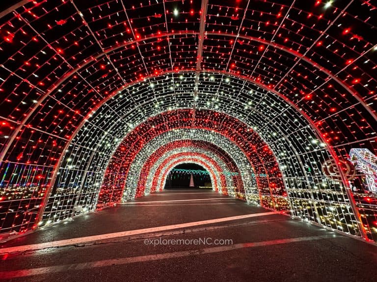 A vibrant red and white illuminated tunnel of Christmas lights at the Charlotte Motor Speedway Christmas event.