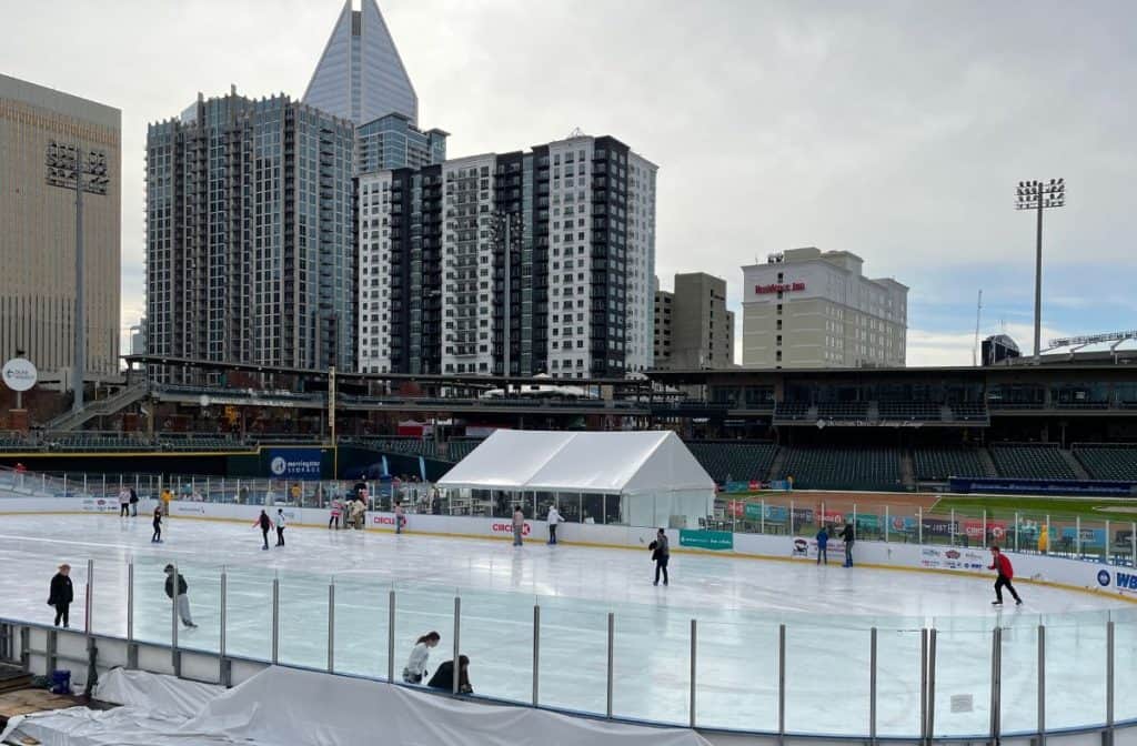 Ice skaters at Truist Field in Charlotte, NC, with a city skyline backdrop during the Light the Knights Festival.